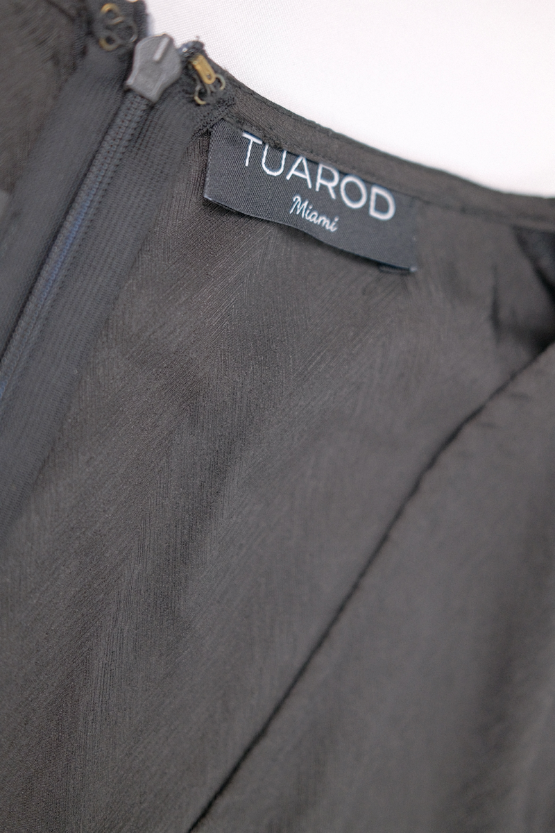 Vestido negro corto de capas, mangas largas, cinturón anudado y cremallera en la espalda